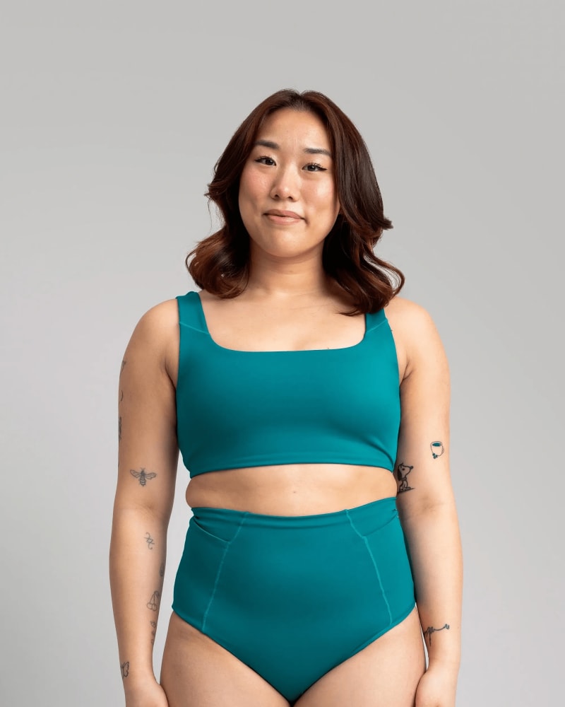 Front of a model wearing a size 5X surf's up swim bikini bottom in lagoon by alder apparel. | dia_product_style_image_id:296217